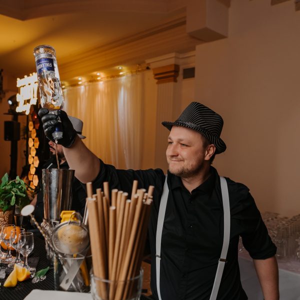 Barman pracuje przy barze, przygotowując koktajle dla gości