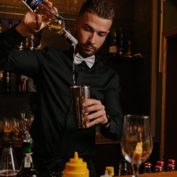 Barman nalewa składniki do koktajlu przy barze