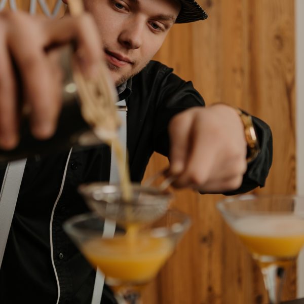 Barman nalewa koktajl do kieliszków podczas obsługi baru